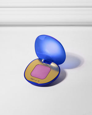 VIOLETTE_FR is embossed on the gold pan of an open, heart-shaped compact with a translucent royal blue case and a square of matte lavender-pink powder.