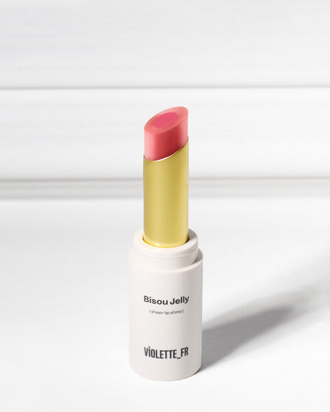 Violette_FR Bisou Jelly (sheer lip shine) in a two-toned pink shade, with a gold inner tube, standing upright.