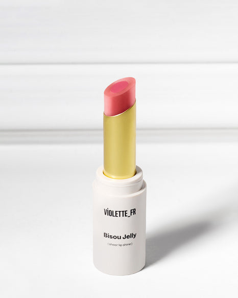Violette_FR Bisou Jelly (sheer lip shine) in a two-toned pink shade, with a gold inner tube, standing upright.