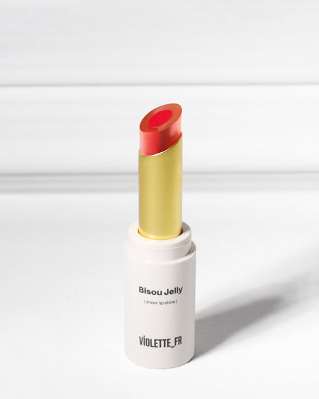 Bisou Jelly (sheer lip shine) by VIOLETTE_FR, a red-orange lip shine in a white tube with a gold base.