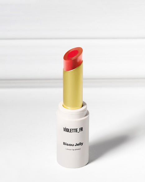 Bisou Jelly (sheer lip shine) by VIOLETTE_FR, a red-orange lip shine in a white tube with a gold base.