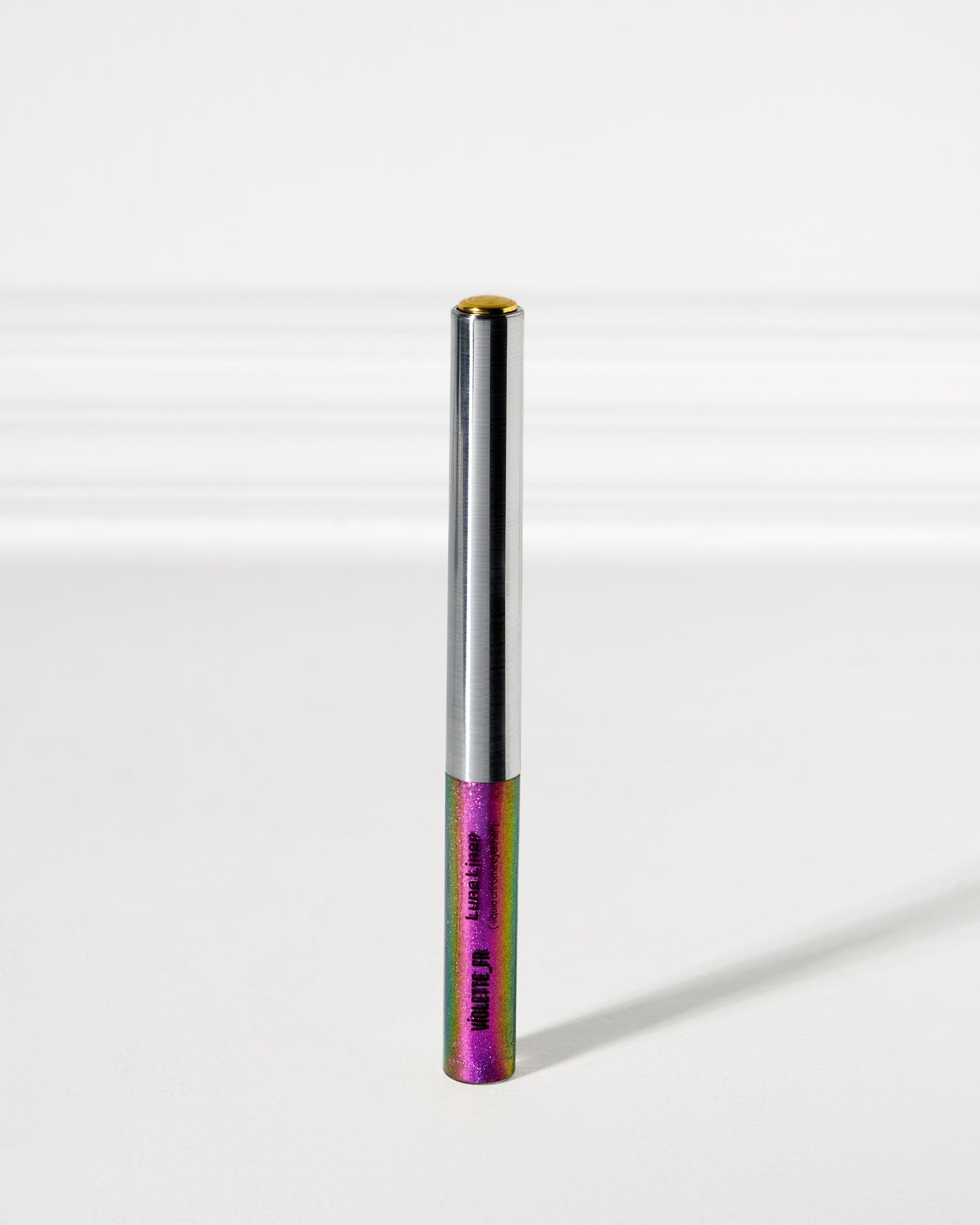 VIOLETTE_FR Lune Liner liquid chrome eyeliner, in an iridescent tube shimmering with purple, pink, green, and blue glitter, with a silver metallic top and gold cap.