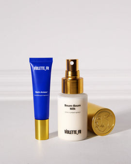 Violette_FR Balm Amour nourishing lip treatment in a blue tube and Boum-Boum Milk 3-in-1 cream spray in a white bottle with a gold cap featuring an embossed face.