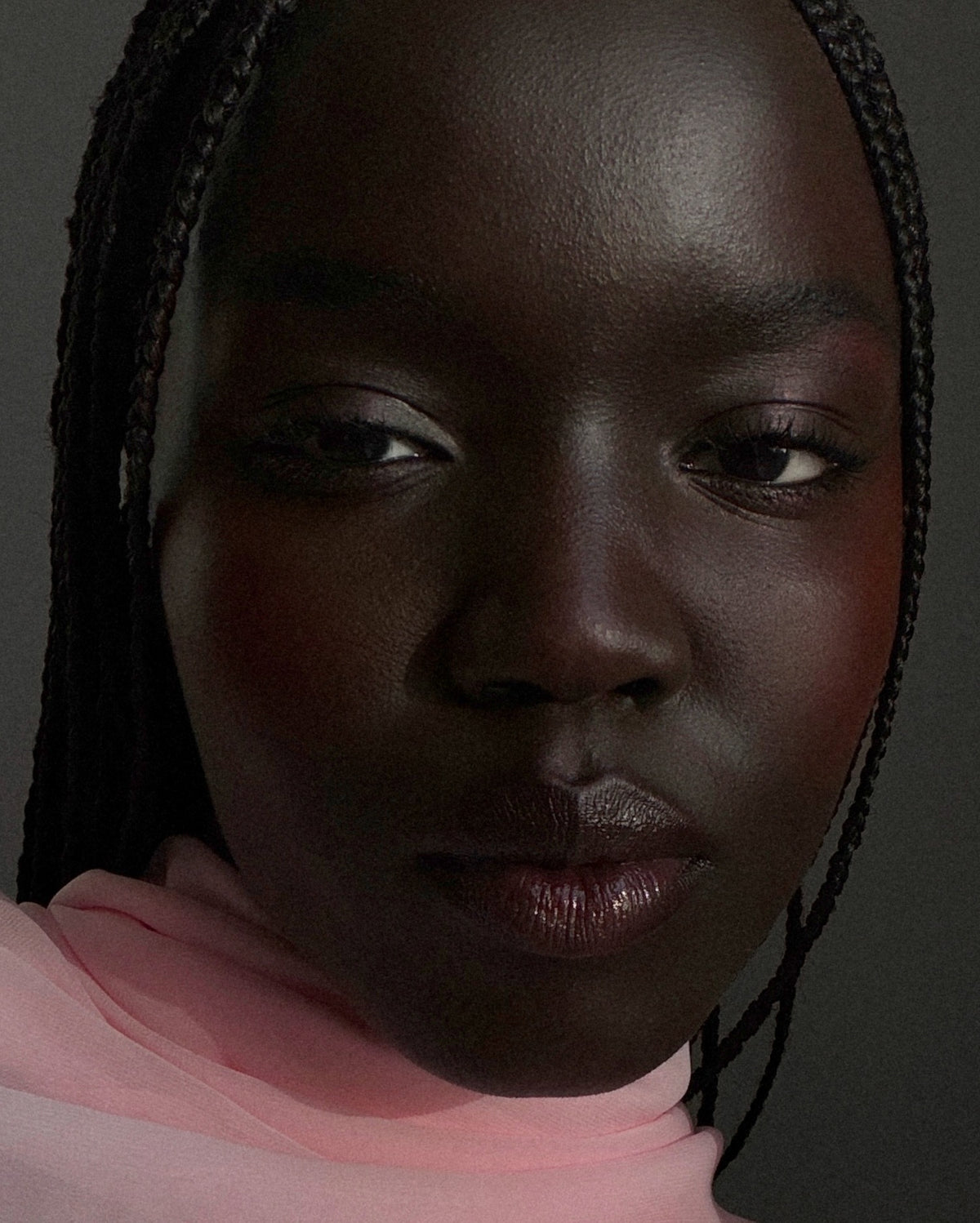Woman with deep skin tone has flush cheeks with a red blush that allows her natural skin tone underneath to peak through and blend with the blush color. 