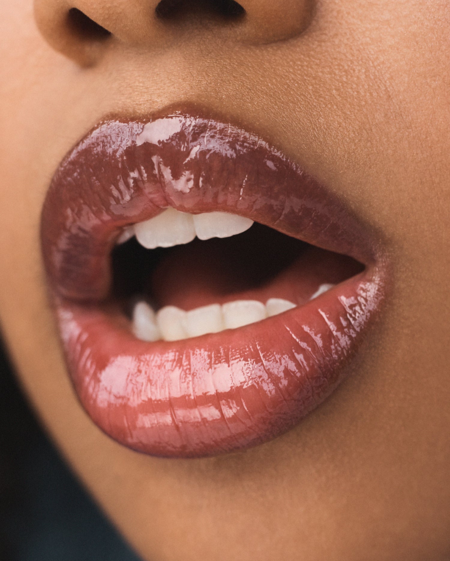 A close-up of glossy brown lips that are slightly parted.