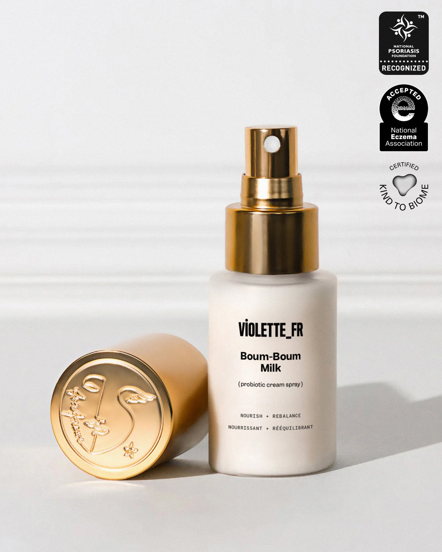 VIOLETTE_FR Boum-Boum Milk (3-in-1 cream spray) in a white bottle with a gold pump and an embossed gold cap. The product is recognized by the National Psoriasis Foundation, accepted by the National Eczema Association, and certified Kind to Biome.