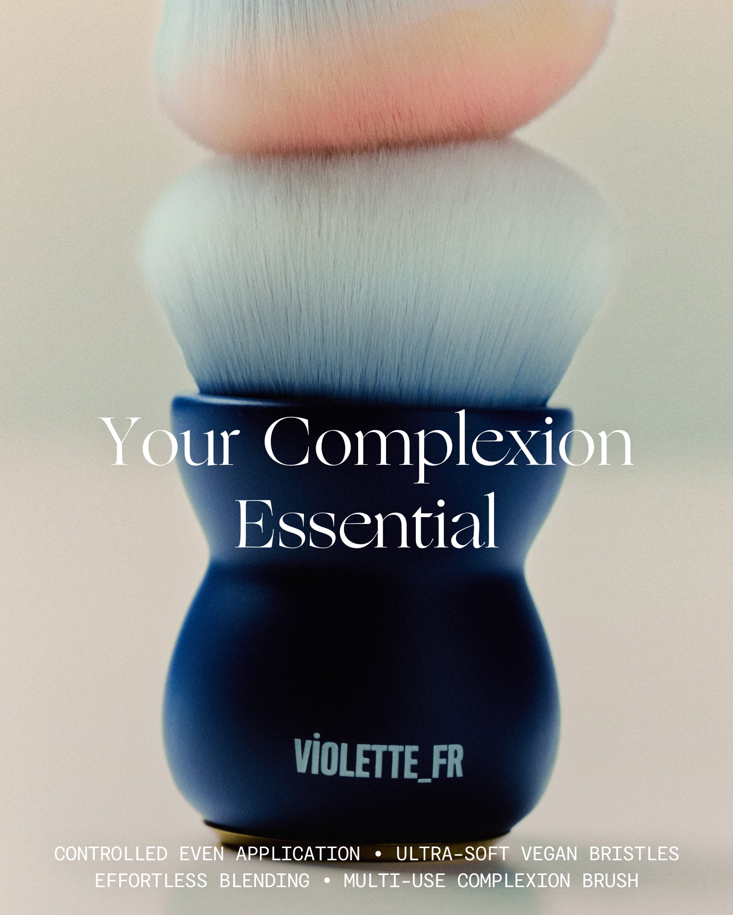 Le Kabuki - Violette_FR's 'Your Complexion Essential' multi-use complexion brush features ultra-soft vegan bristles for controlled, even application and effortless blending. The brush has a dark blue ergonomic handle and white bristles fading to light blue and pink tips. - Image 2 of 10