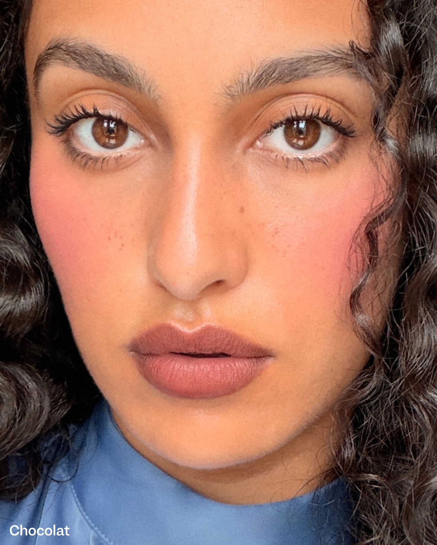 Chocolat: Close-up of a model with medium skin tone wearing cool brown lipstick with pink and red undertone from her natural lip color. - Bisou Balm