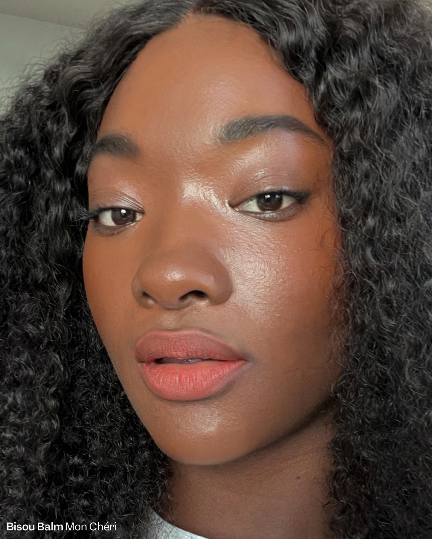 Mon Chéri. Close-up of a woman with deep skin tone wearing a warm terracotta lipstick shade. - Bisou-Bisou Lip Duo