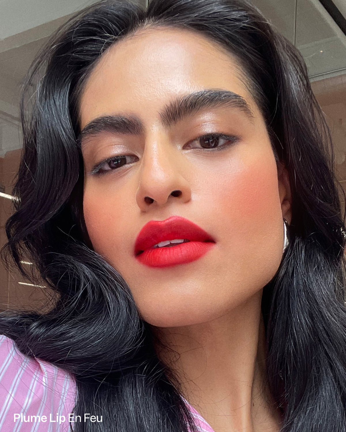 Duo Plume Lip & Bisou Balm - Plume Lip En Feu. Close-up of a model with medium skin tone wearing bright red lipstick and blush. - Image 5 of 15