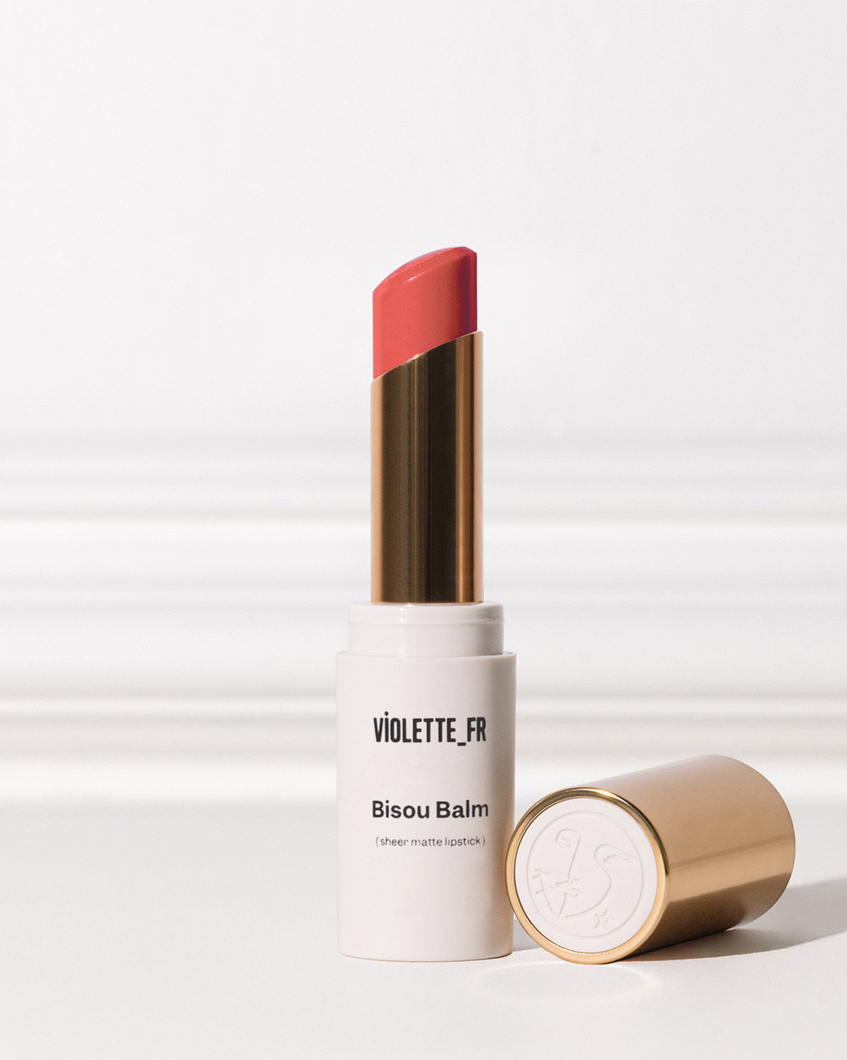 Bisou Balm - Chocolat - Bisou Balm (sheer matte lipstick) by VIOLETTE_FR, a coral-pink lipstick in a white and gold tube with the cap off. - Image 157 of 157